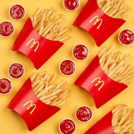 Golden French fries arranged in precise rows alongside containers of vibrant ketchup, creating an enticing pattern of repetition. A perfect sample of our social media content creation.