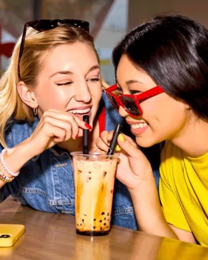 friends-sharing-bubble-tea-bbt-edojapan wo friends sharing a bubble tea drink with tapioca pearls, smiling and enjoying the moment together.